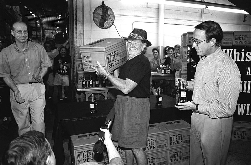 Willie Nelson hoists a case of the Old Whiskey River Kentucky Straight Bourbon at Heaven Hill Distillery in Bardstown, Kentucky. (Photo: Old Whiskey Bourbon/Getty Images)